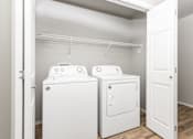 Thumbnail 23 of 26 - Two white washing machines in a laundry room.