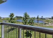 Thumbnail 25 of 26 - A balcony overlooks a river and a field.
