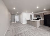 Thumbnail 11 of 26 - A spacious living room with a television and a kitchen area.