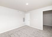 Thumbnail 16 of 26 - A room with a carpeted floor and a door on the left side.