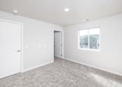 Thumbnail 14 of 26 - A white room with a carpeted floor and a window showing a house outside.