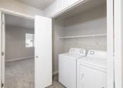 Thumbnail 22 of 26 - A white washer and dryer in a small laundry room.