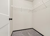 Thumbnail 22 of 43 - A white closet with a black door and carpeted floor.
