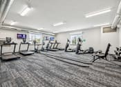 Thumbnail 6 of 21 - A gym with treadmills, exercise bikes, and other equipment.