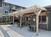 Thumbnail 19 of 20 - Outdoor kitchen area with barbecue and dining table.