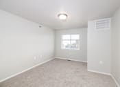 Thumbnail 3 of 22 - A spacious, empty room with a window and carpeted floor.