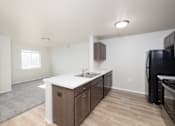 Thumbnail 19 of 22 - A kitchen with a black refrigerator, sink, and cabinets.