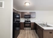 Thumbnail 5 of 22 - A kitchen with a black refrigerator, stove, and microwave.