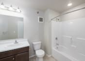 Thumbnail 6 of 22 - A white bathroom with a toilet, sink, and bathtub.