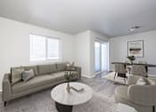 Thumbnail 1 of 26 - A living room with a grey couch, a white coffee table, and a grey chair.