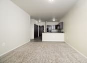 Thumbnail 1 of 26 - A spacious room with a kitchen area in the background.