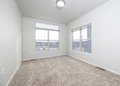 Thumbnail 6 of 26 - A room with a carpeted floor and two windows.