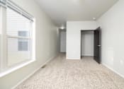 Thumbnail 3 of 26 - A room with a carpeted floor, a window with blinds, and a door leading to another room.