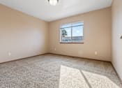 Thumbnail 57 of 64 - A room with a carpeted floor and a window showing a tree and a building outside.