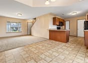 Thumbnail 4 of 64 - A spacious living room with a kitchen area in the background.