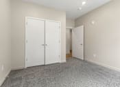Thumbnail 10 of 32 - A room with two white doors and a carpeted floor.