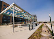 Thumbnail 35 of 41 - A modern outdoor seating area with a glass roof and a stone wall.