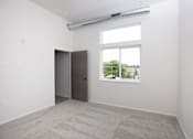 Thumbnail 12 of 39 - A room with a carpeted floor, a door, and a window.