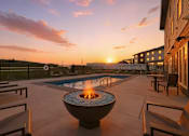 Thumbnail 21 of 44 - A fire pit sits in the middle of a patio with chairs around it.