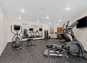 Thumbnail 25 of 44 - A spacious gym with a variety of equipment including treadmills, elliptical machines, and a television.