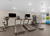 Thumbnail 24 of 44 - A gym with treadmills, exercise bikes, and a television.