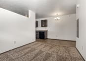 Thumbnail 53 of 59 - A room with a carpeted floor and a kitchen area in the background.