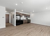 Thumbnail 33 of 44 - the living room and kitchen of an apartment with wood flooring and black appliances