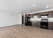 Thumbnail 34 of 44 - an empty kitchen and living room with black appliances and wood flooring