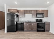 Thumbnail 36 of 44 - an empty kitchen with black appliances and wooden cabinets