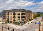 Thumbnail 41 of 42 - A street view of a multi-story building with a traffic light in front of it.