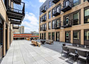 Thumbnail 12 of 42 - A patio with a table and chairs is surrounded by balconies.