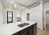 Thumbnail 35 of 42 - A modern kitchen with a white countertop and a stainless steel sink.