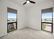 Thumbnail 23 of 42 - A room with a ceiling fan and two windows overlooking a cityscape.