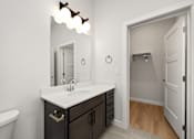 Thumbnail 24 of 42 - A bathroom with a sink, mirror, and a white door.
