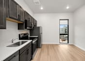 Thumbnail 27 of 42 - A kitchen with black cabinets and a window showing a building.