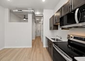 Thumbnail 28 of 42 - A kitchen with a black stove top oven and a black microwave above it.
