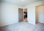 Thumbnail 6 of 21 - A room with a carpeted floor and a doorway leading to another room.