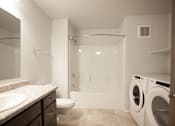 Thumbnail 10 of 21 - A white bathroom with a sink, toilet, and washing machine.