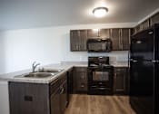 Thumbnail 11 of 21 - A kitchen with black appliances and wooden cabinets.