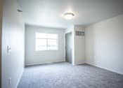 Thumbnail 13 of 21 - A spacious room with a window and carpeted floor.