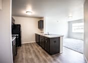 Thumbnail 20 of 21 - A kitchen with a black fridge and wooden floors.