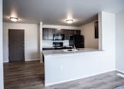 Thumbnail 21 of 21 - A kitchen with a black refrigerator and a countertop with a sink.