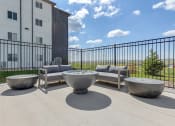 Thumbnail 33 of 35 - an outdoor patio with couches and tables and a building in the background