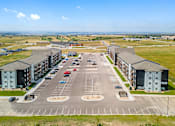 Thumbnail 12 of 38 - A parking lot with cars and apartment buildings in the background.