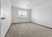 Thumbnail 27 of 38 - A room with a carpeted floor and a window showing a view of a house.