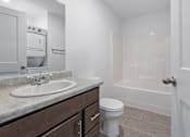 Thumbnail 35 of 38 - A white bathroom with a sink, toilet, and bathtub.