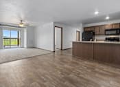 Thumbnail 22 of 38 - A spacious living room with wooden flooring and modern appliances in the kitchen.
