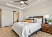 Thumbnail 35 of 43 - A bedroom with a large bed, a ceiling fan, and a nightstand with a plant on it.