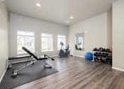 Thumbnail 6 of 41 - A home gym with a bench, weights, and exercise balls.
