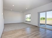 Thumbnail 18 of 54 - a living room with white walls and wood floors and a sliding glass door